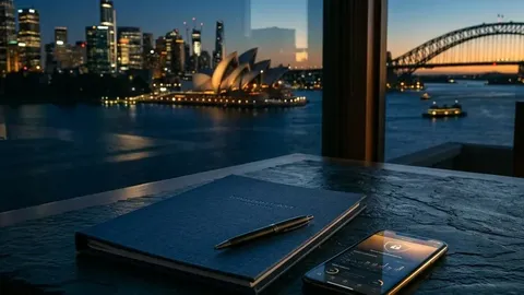 A report folder and smartphone overlooking Sydney harbour in blue and amber light